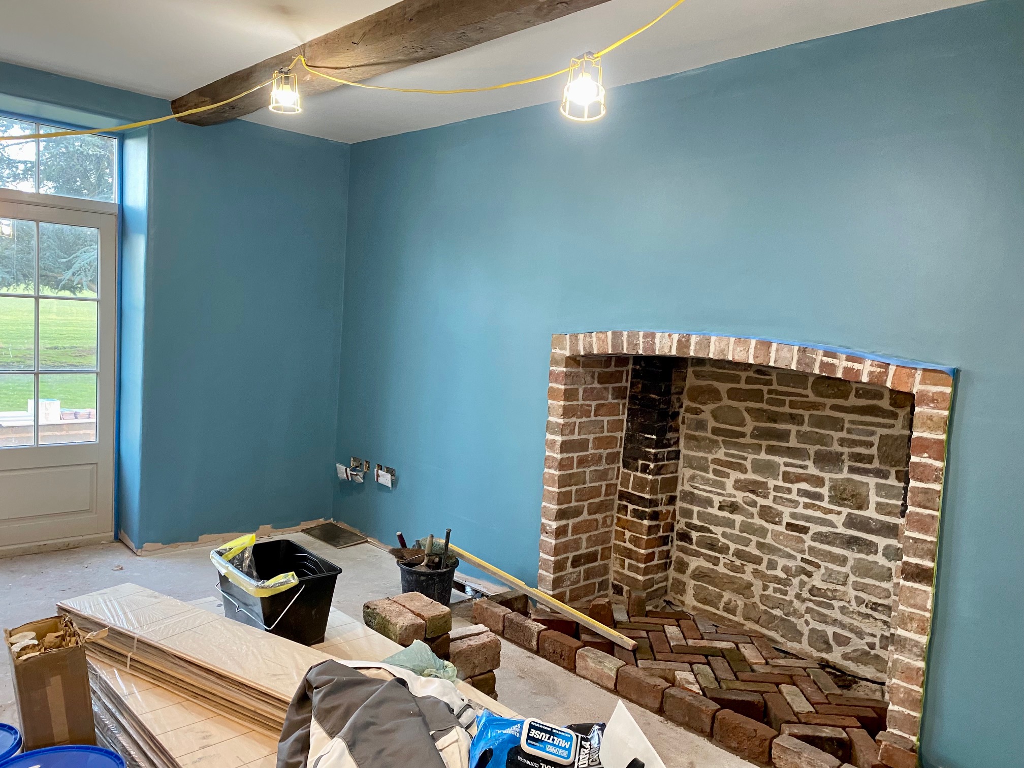 Living room mid-decoration in a warm teal blue with a brick fireplace