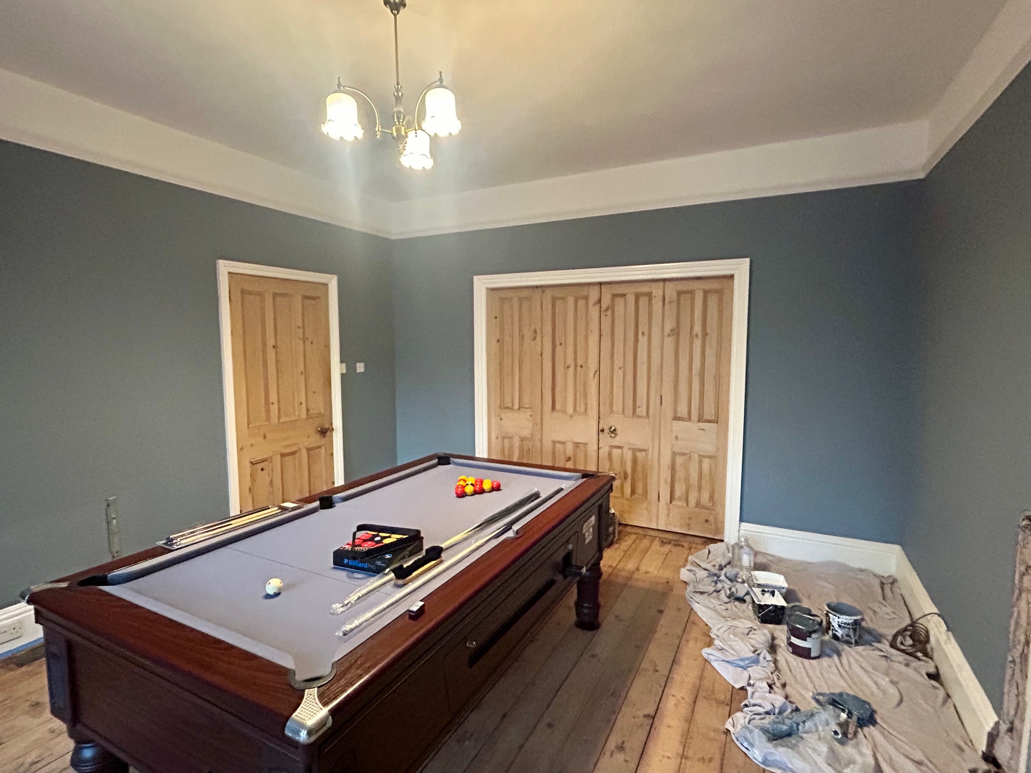 Games room painted in a deep petrol blue with pine doors